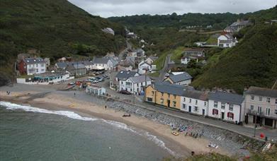 A Welsh fishing village with a small beach and wooded cliffs on either side