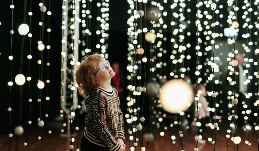 Child admiring bright lights in an art installation.