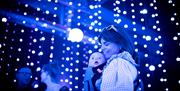 Woman holding baby in front of blue light display, showcasing tender moment between mother and child.