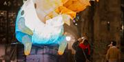 Giant multi coloured inflatable creature in a dark church garden