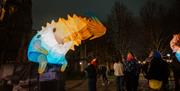 Giant multi coloured inflatable creature in a dark church garden